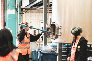 A guest of our 2024 International Women's Collaboration Brew Day digs out our mash tun at Five Points