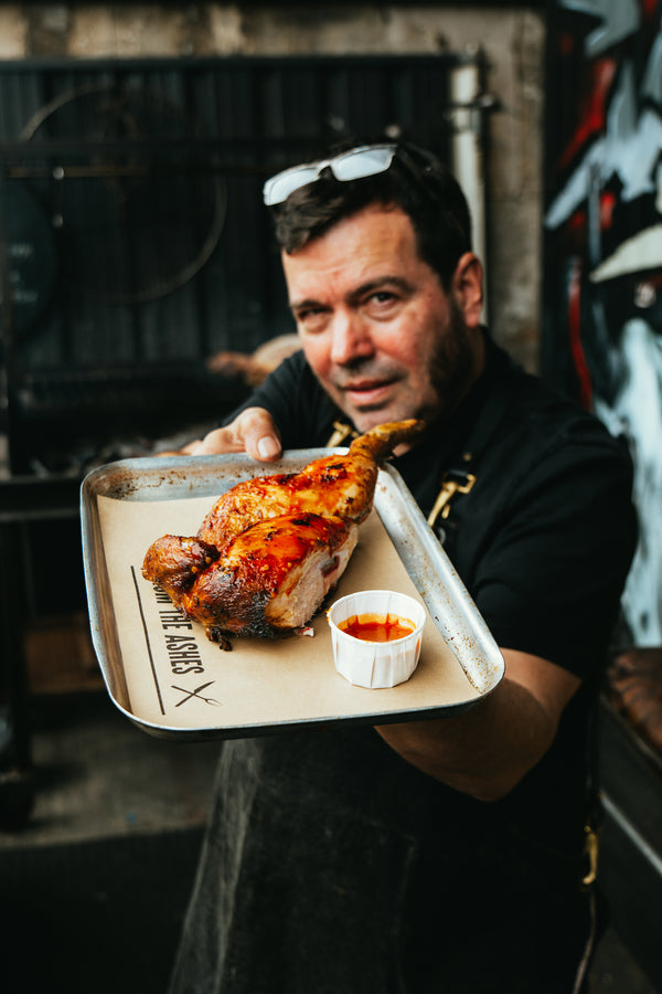 Martin of From The Ashes holds a half chicken dish. Photo by Studio Highball