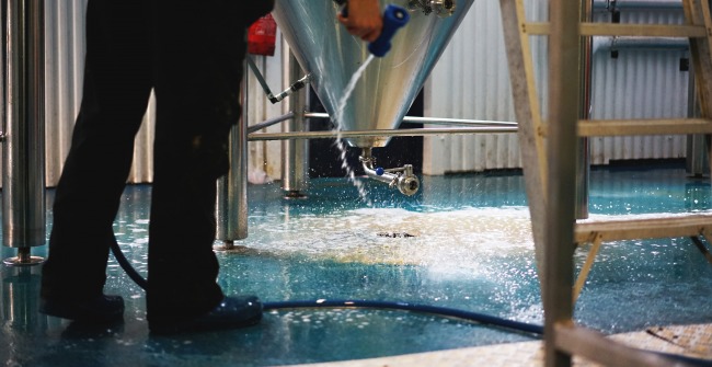 A brewer hose-washing the floor of The Five Points brewery in Hackney