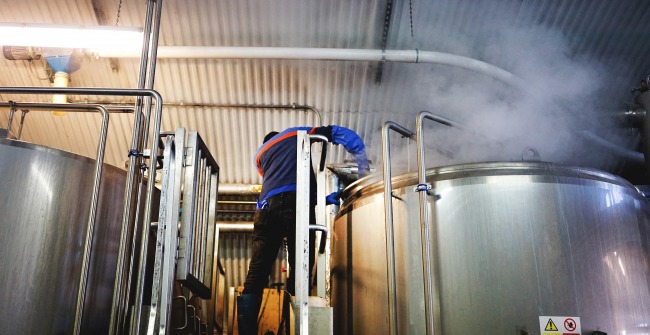 A brewer adds hops to the kettle at The Five Points brewery in Hackney, London