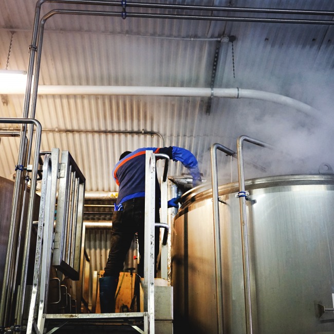 A brewer adds hops of the kettle at the Five Points Brewery in Hackney, London