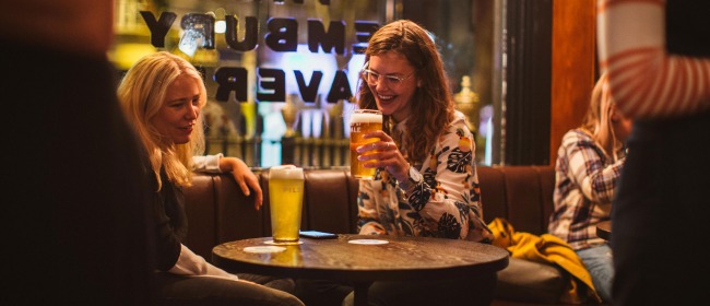 Two women laughing and drinking pints of Five Points beer in the window seat at The Pembury Tavern in Hackney